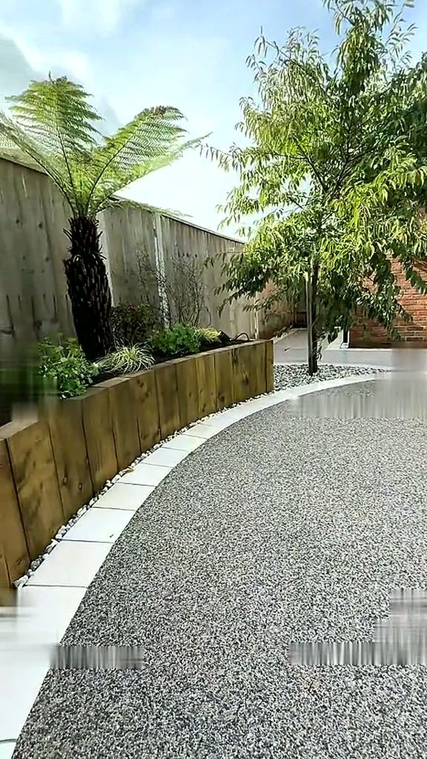 Finished resin bound garden surface with a pale curved kerb and raised sleeper bed