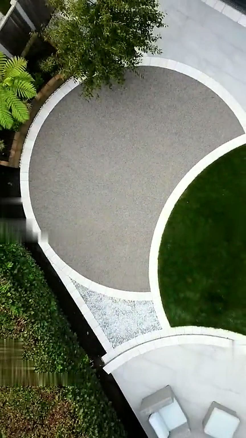 Aerial view of a circular lawn set into a resin bound garden with porcelain terrace