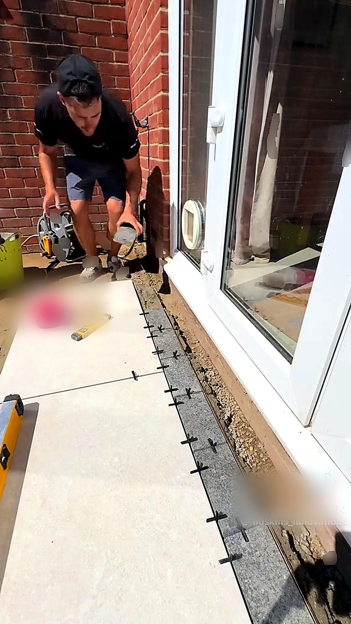 Plate compactor consolidating ground beside patio doors