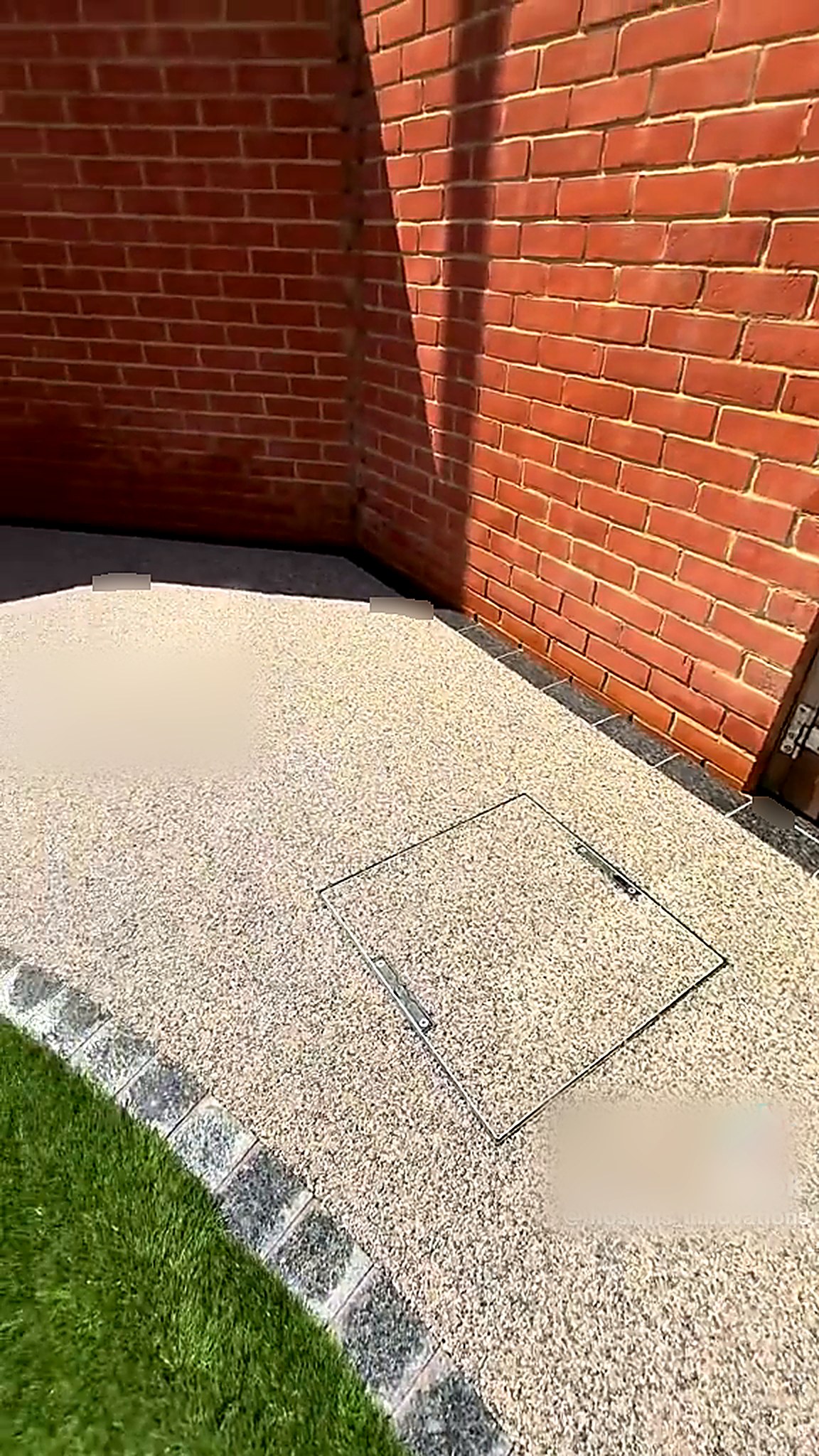 Completed resin bound area with granite sett framed manhole cover