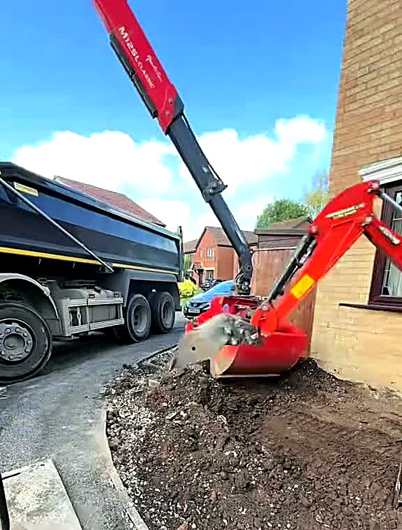 Mini excavator lifting old driveway material into a grab lorry
