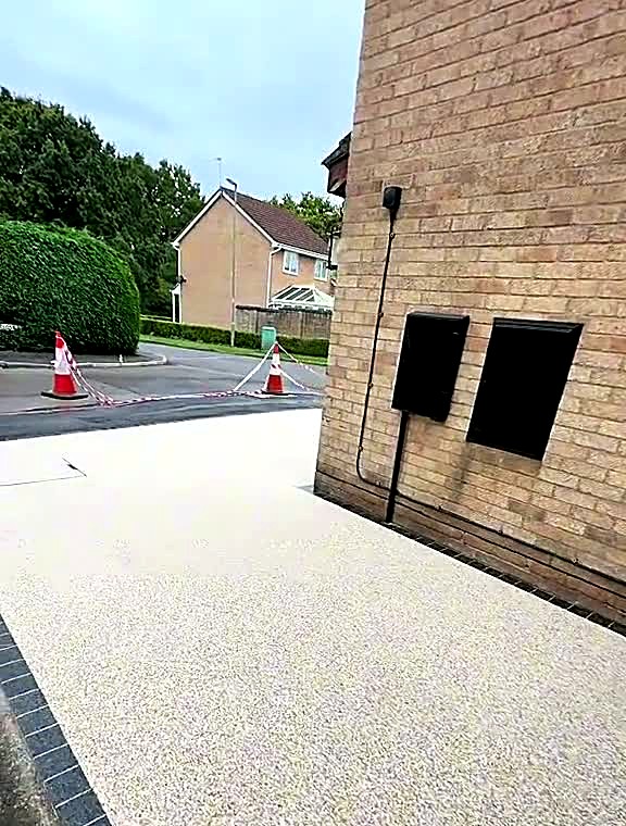 Finished pale resin bound driveway running to a charcoal block border