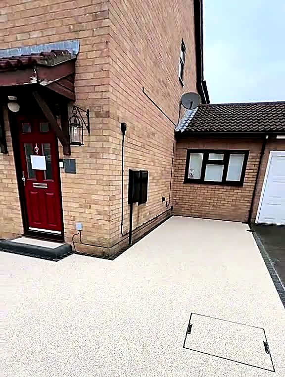 Completed resin driveway sweeping to a red front door with dark block border