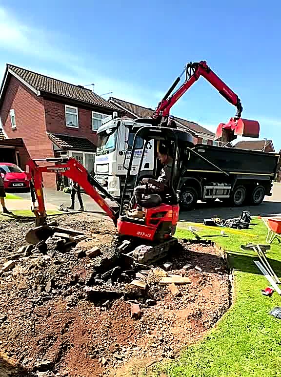Mini excavator lifting broken tarmac from a front driveway