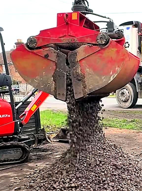 Grab lorry bucket loading driveway spoil at the kerb