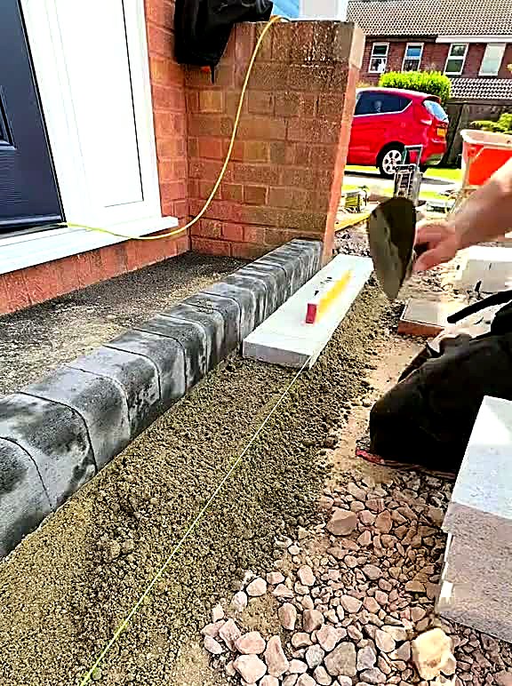 Charcoal kerb line bedded on concrete along a driveway boundary