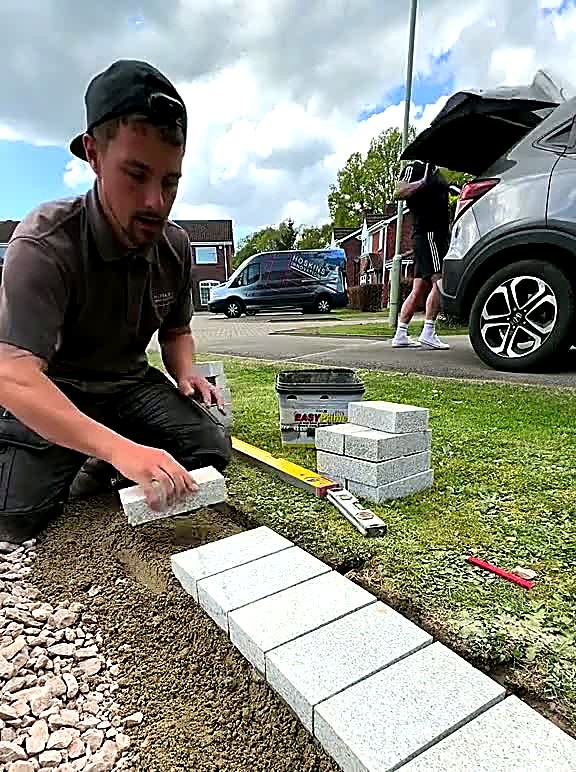 Line of silver granite setts set out to a string line beside a lawn