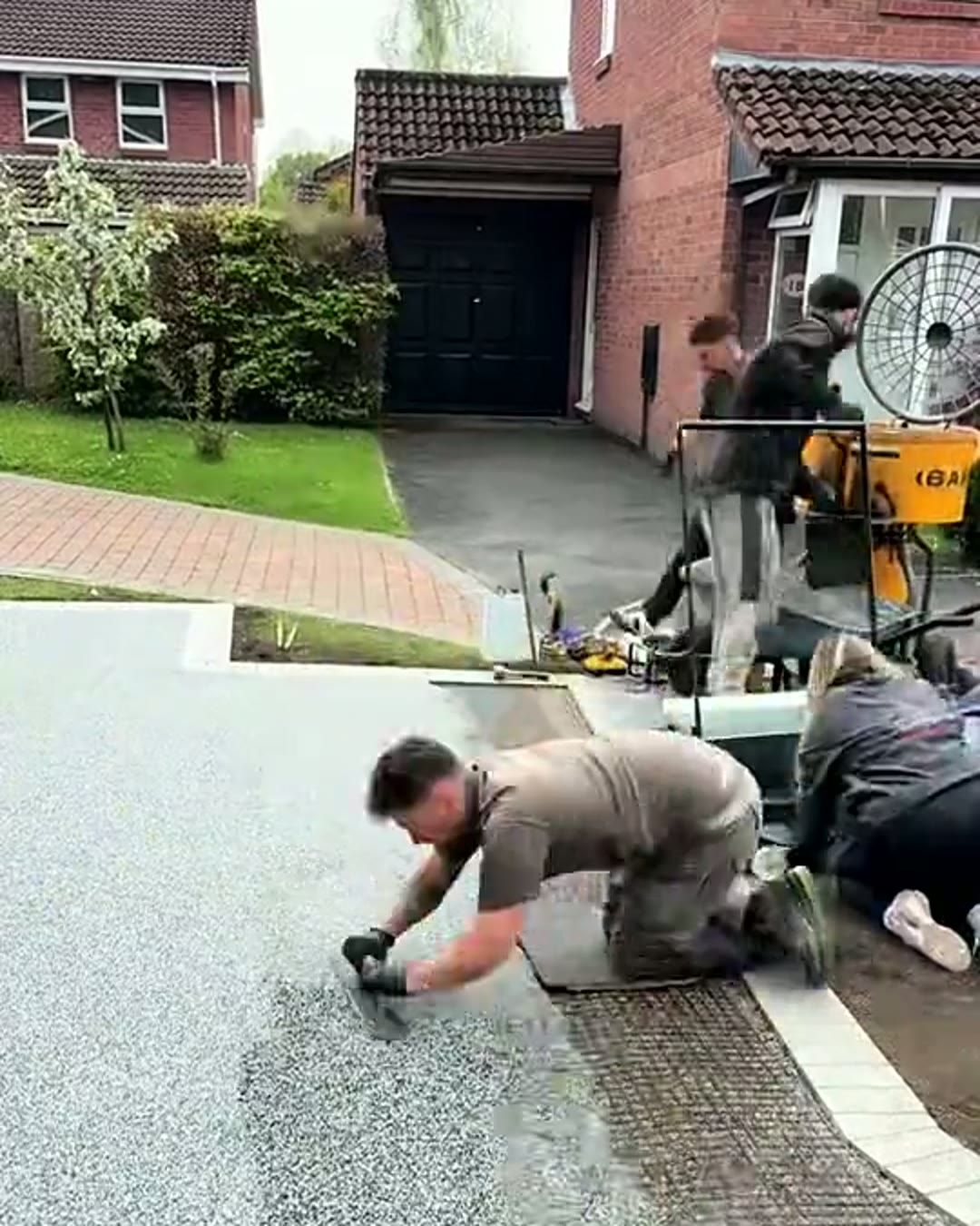 Installer kneeling to hand-trowel the resin driveway surface smooth