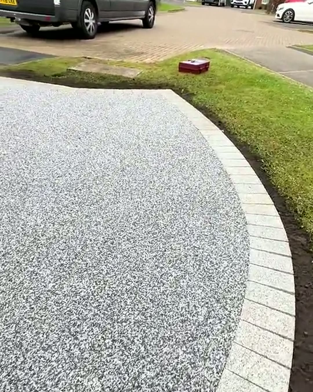 Finished silver-grey resin driveway with a granite sett border and lawn edge