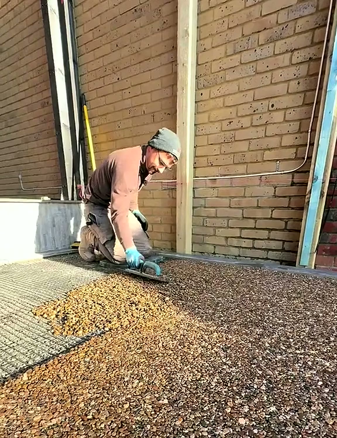 Installer spreading resin bound aggregate around porcelain inlay slabs