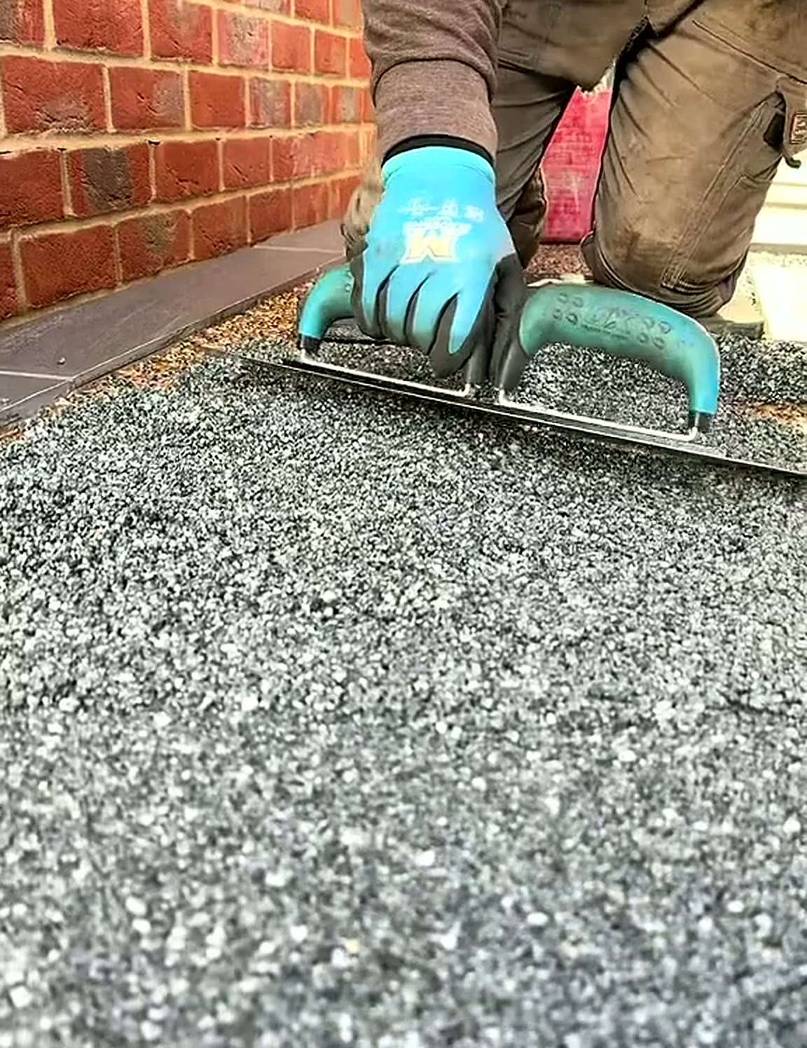 Trowel smoothing grey resin bound aggregate to a flat finish